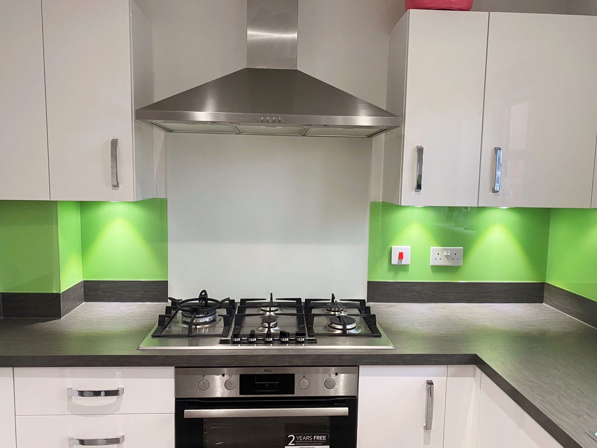 Painted colour splashback with green colour and over hang lights design fitted by glass inspirations ltd